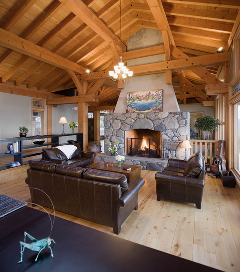 Great room at Halo Ridge Recovery with a river-rock fireplace lit, leather sofas, guitar in the corner, and light wood floors